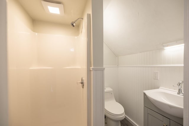 bathroom featuring a shower, a wainscoted wall, toilet, vaulted ceiling, and vanity