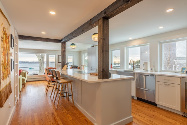 kitchen with dishwasher, beam ceiling, light wood-style floors, white cabinetry, and black electric cooktop