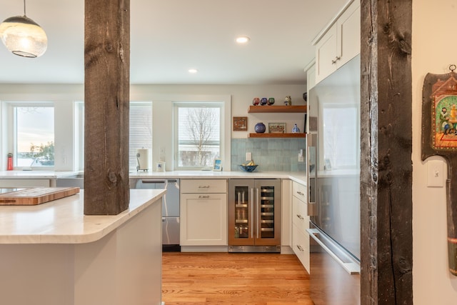 kitchen featuring beverage cooler, a healthy amount of sunlight, light countertops, and light wood-style flooring