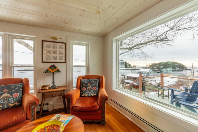 sitting room featuring wood finished floors, a water view, baseboards, and a baseboard radiator