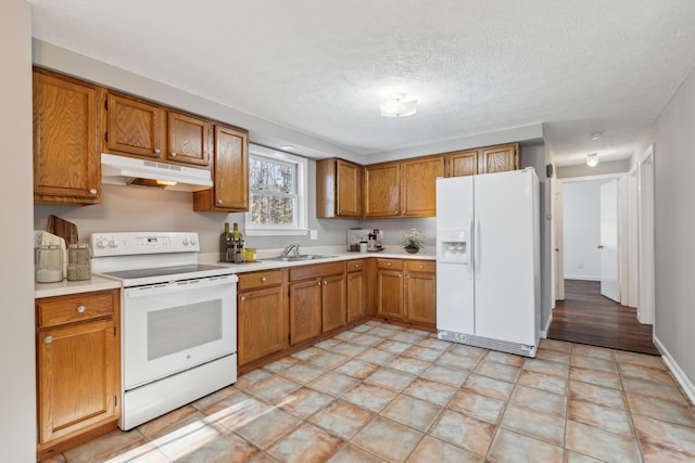 kitchen with white appliances, sink, and a textured ceiling