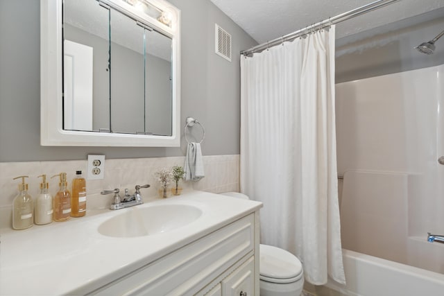 full bathroom with shower / bathtub combination with curtain, vanity, toilet, and a textured ceiling