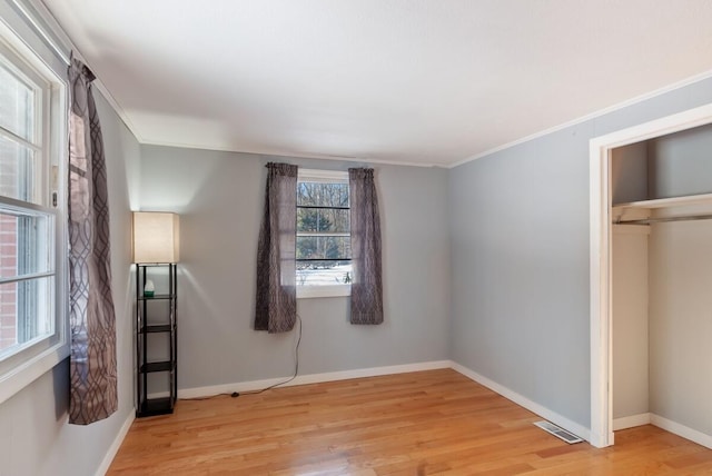 unfurnished bedroom with crown molding and light wood-type flooring