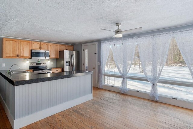 kitchen with sink, ceiling fan, stainless steel appliances, a textured ceiling, and light hardwood / wood-style flooring