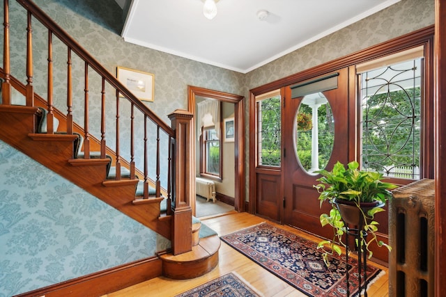 foyer entrance featuring ornamental molding, radiator heating unit, and light hardwood / wood-style floors