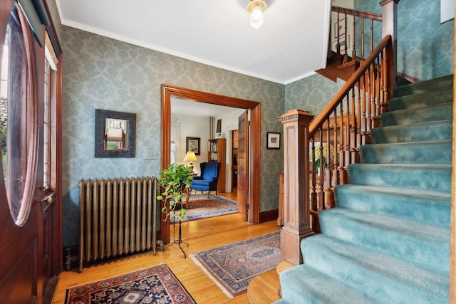 foyer entrance featuring radiator, crown molding, and hardwood / wood-style floors