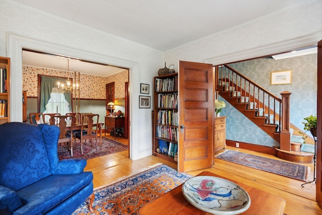 living room with a notable chandelier, crown molding, and wood-type flooring