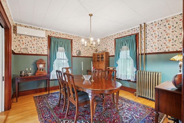 dining room featuring radiator, a notable chandelier, a wall unit AC, and light hardwood / wood-style floors