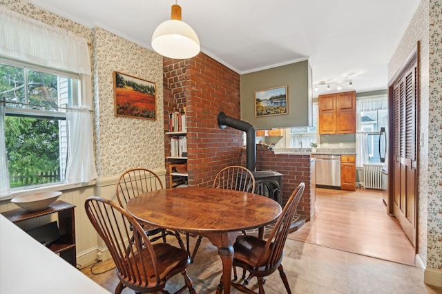 dining area featuring crown molding, a wood stove, track lighting, and radiator