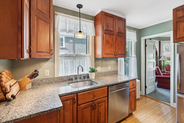 kitchen with stone counters, pendant lighting, sink, stainless steel appliances, and light hardwood / wood-style flooring