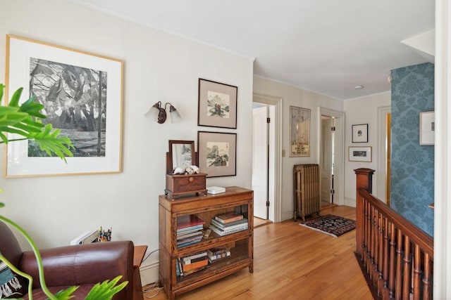 hallway with crown molding, radiator, and light hardwood / wood-style flooring