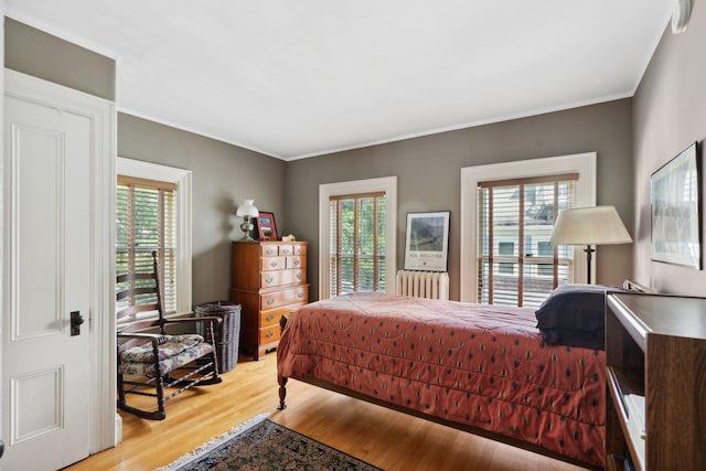 bedroom with multiple windows, radiator, and light hardwood / wood-style flooring