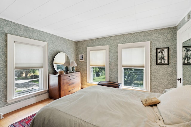 bedroom featuring a baseboard radiator, light hardwood / wood-style floors, and multiple windows