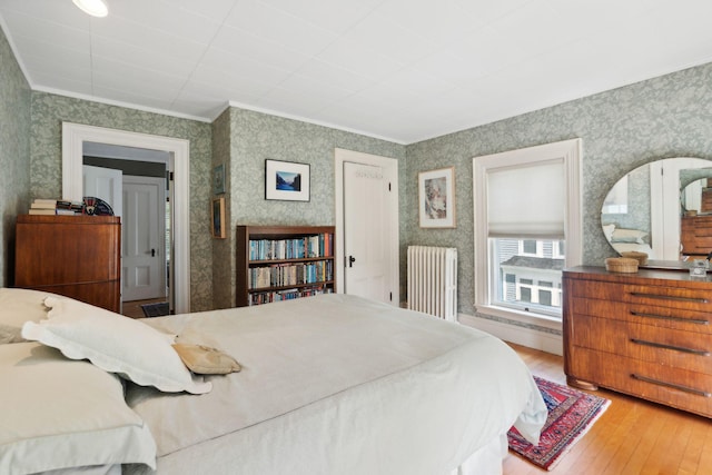 bedroom featuring crown molding, radiator heating unit, and wood-type flooring