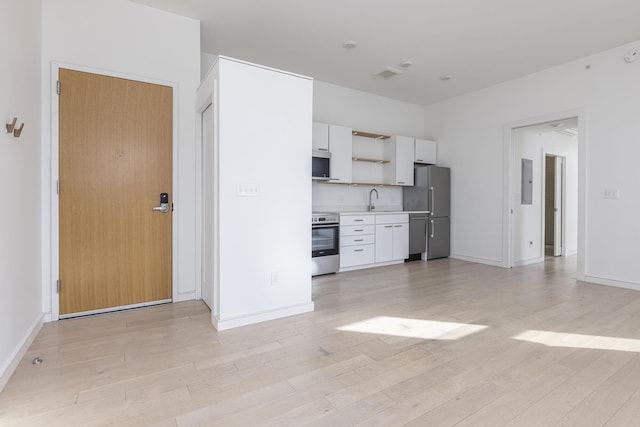 kitchen featuring stainless steel appliances, white cabinetry, sink, and light hardwood / wood-style floors