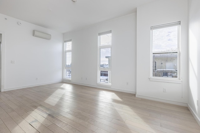 spare room with light hardwood / wood-style floors and a wall unit AC