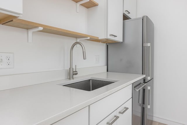 kitchen with white cabinetry, stainless steel fridge, and sink