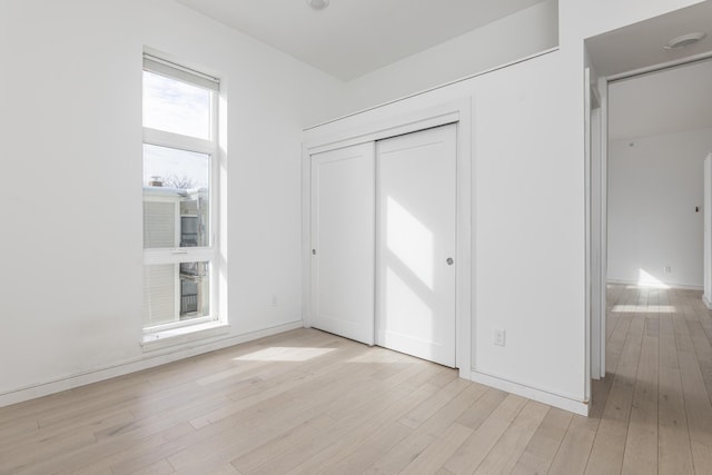 unfurnished bedroom with light hardwood / wood-style floors and a closet