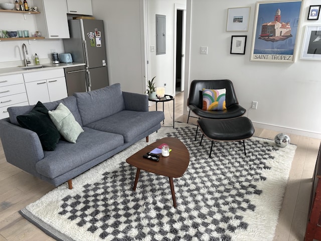 living room featuring indoor wet bar, electric panel, and light hardwood / wood-style flooring