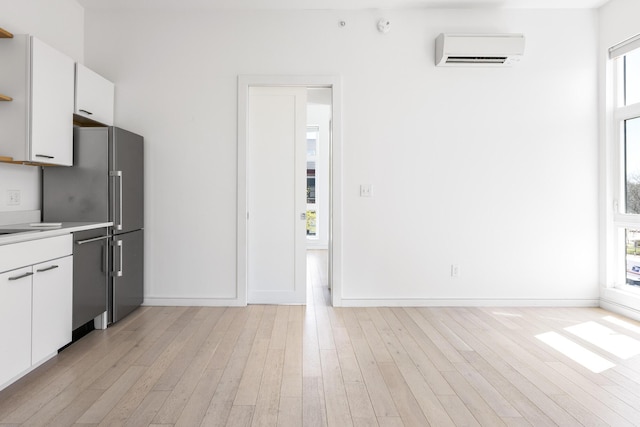 1 Joy Pl Unit 3A, Portland, ME 04102 - kitchen with light wood-style floors, an AC wall unit, light countertops, white cabinets, and stainless steel appliances