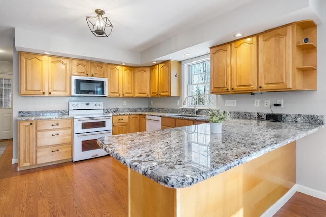 kitchen featuring sink, light stone counters, light wood-type flooring, kitchen peninsula, and white appliances