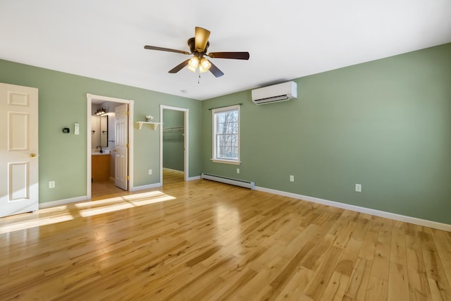 unfurnished bedroom with an AC wall unit, light hardwood / wood-style flooring, a walk in closet, baseboard heating, and a closet