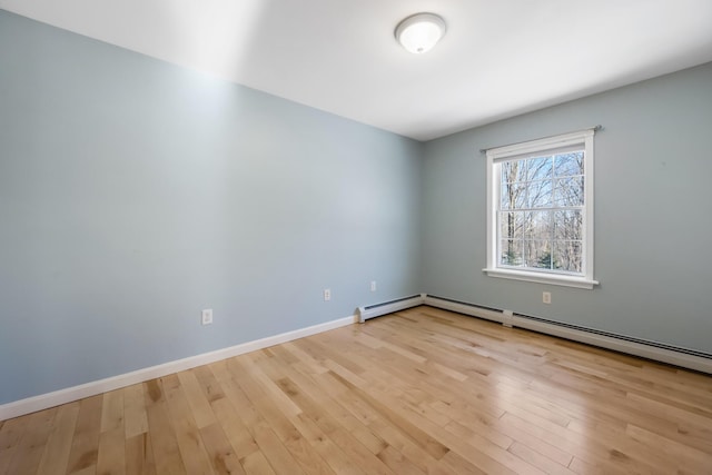 empty room with a baseboard heating unit and light hardwood / wood-style floors