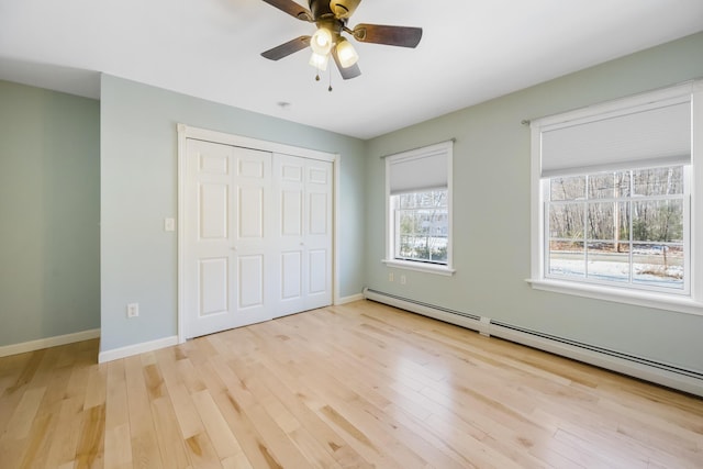 unfurnished bedroom featuring light hardwood / wood-style flooring, a closet, ceiling fan, and baseboard heating