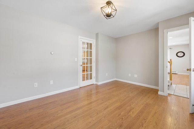 unfurnished room with a baseboard heating unit and light wood-type flooring