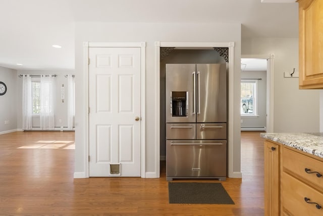 kitchen with high end fridge, light hardwood / wood-style flooring, a healthy amount of sunlight, and light brown cabinets