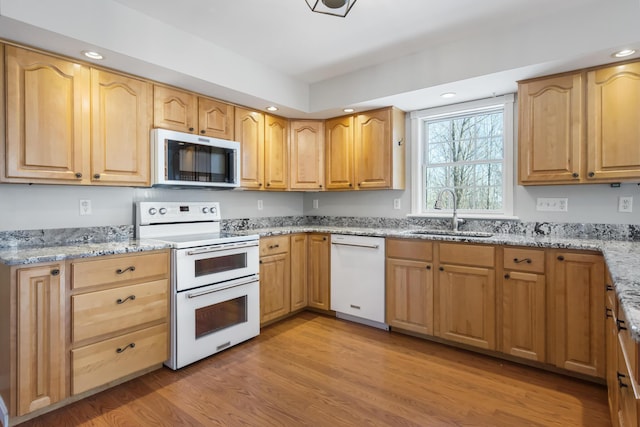 kitchen with light stone countertops, sink, white appliances, and light wood-type flooring