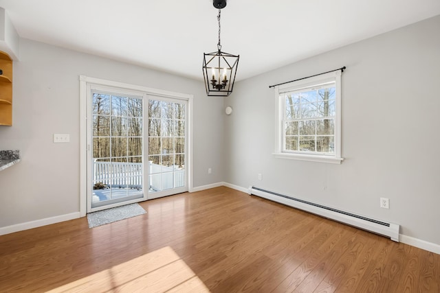 unfurnished dining area featuring hardwood / wood-style flooring, a baseboard heating unit, and a notable chandelier