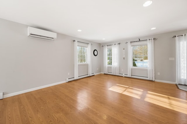 unfurnished room featuring baseboard heating, a wall mounted AC, and light wood-type flooring