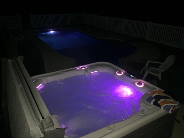 pool at twilight featuring a hot tub