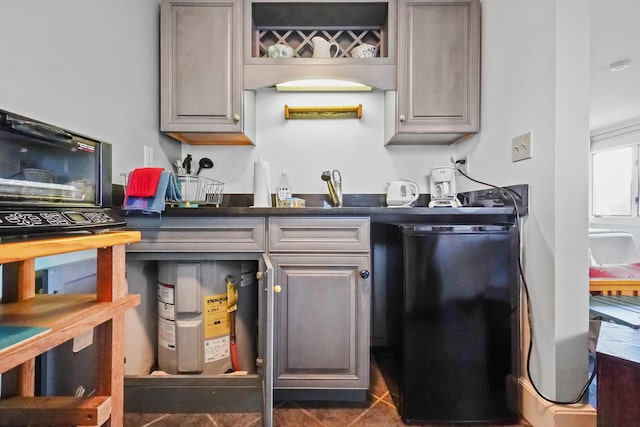 kitchen with gray cabinetry, dark tile patterned floors, and dishwasher