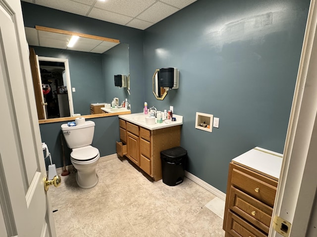 bathroom with a paneled ceiling, vanity, and toilet