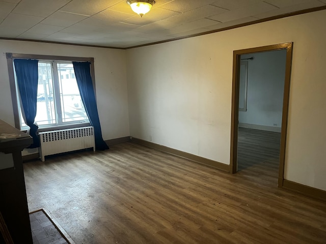 spare room featuring ornamental molding, wood-type flooring, and radiator