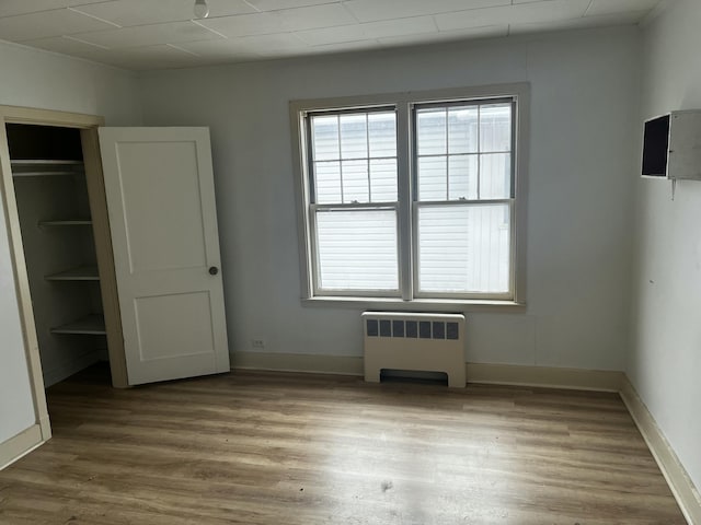 unfurnished bedroom with radiator heating unit, a closet, and wood-type flooring