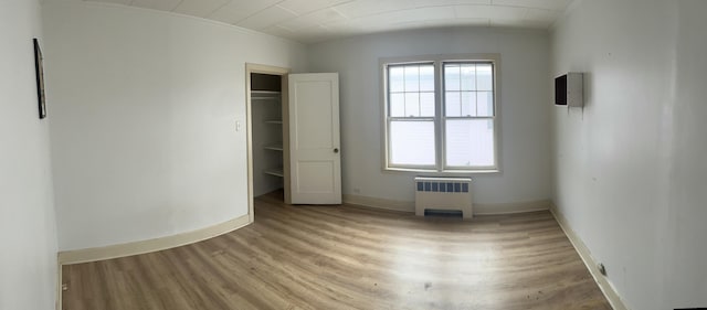 unfurnished bedroom featuring radiator heating unit and wood-type flooring