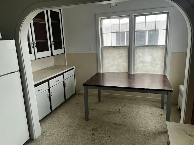 kitchen with white refrigerator, radiator heating unit, tile walls, and white cabinets