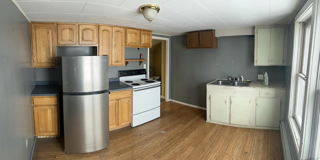 kitchen with stainless steel refrigerator, white electric stove, sink, and hardwood / wood-style floors