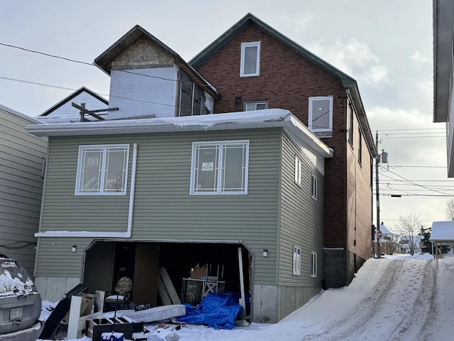 snow covered rear of property with a garage