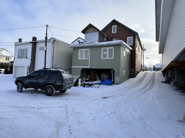 snow covered rear of property with a garage