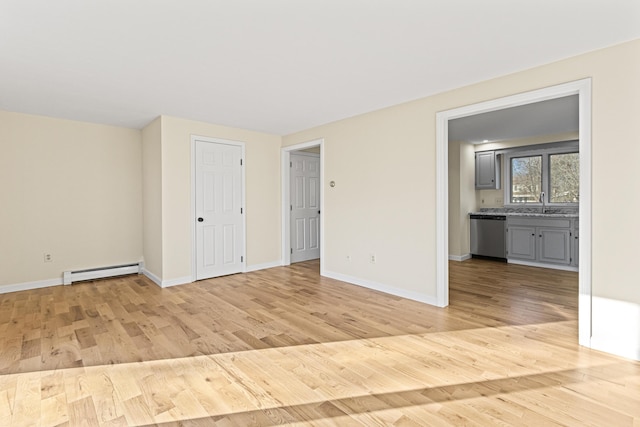 unfurnished room featuring baseboard heating and light hardwood / wood-style floors