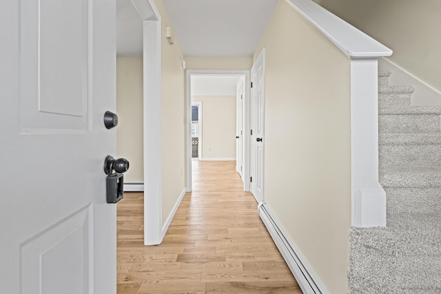 hall with baseboard heating and light wood-type flooring