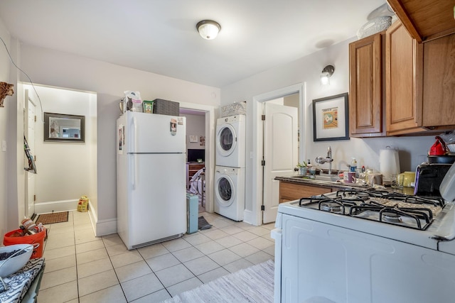 kitchen featuring stacked washer and dryer, white appliances, sink, and light tile patterned floors