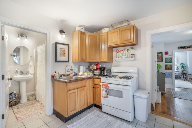 kitchen with light tile patterned flooring, sink, and white range with gas stovetop