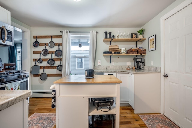 kitchen featuring baseboard heating, a kitchen island, light hardwood / wood-style flooring, and white cabinets