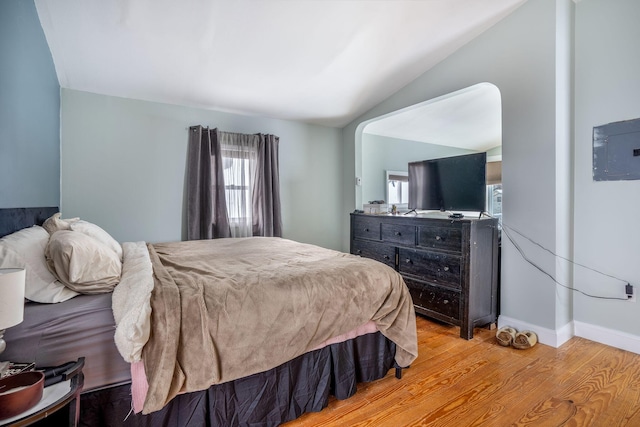 bedroom featuring light hardwood / wood-style flooring, vaulted ceiling, and electric panel