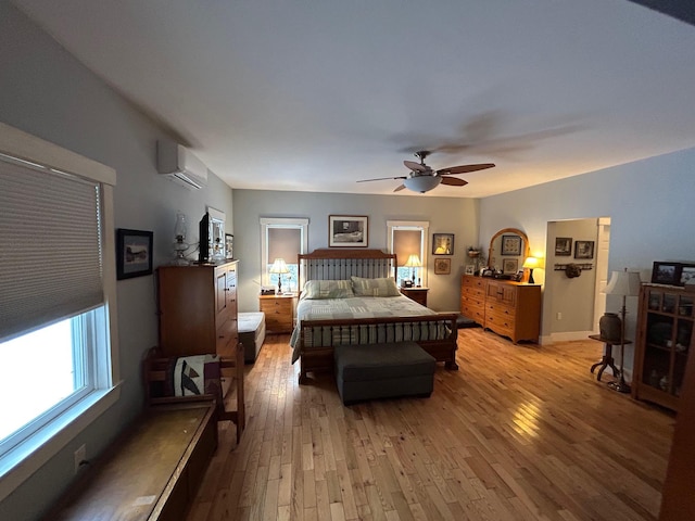 bedroom featuring ceiling fan, a wall mounted AC, and light wood-type flooring